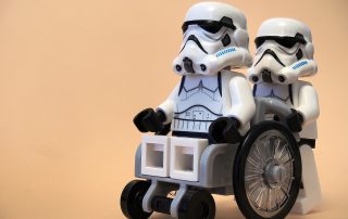 One Star Wars Stormtrooper pushing another one in a wheelchair