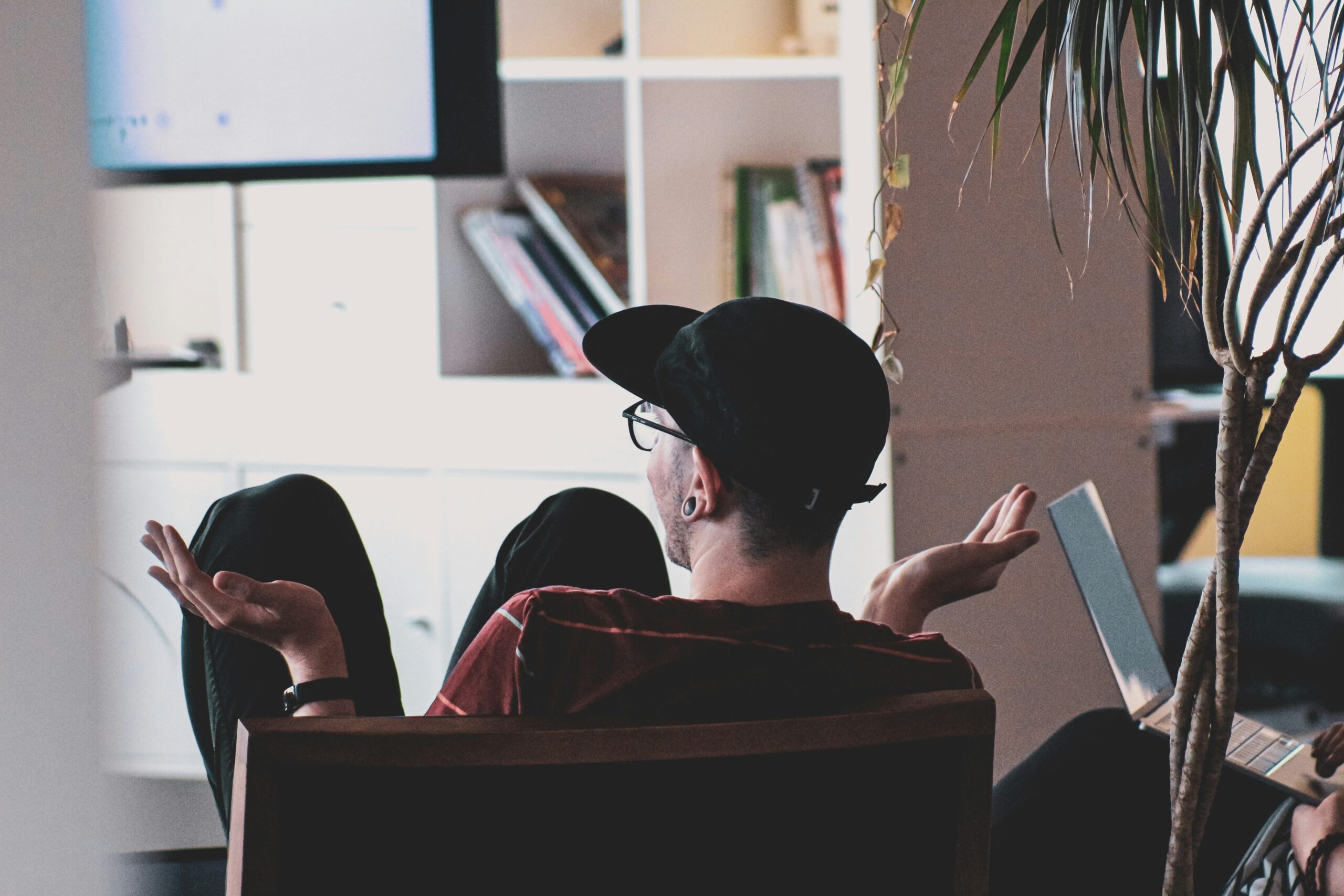 Man sitting in a chair, with his back to us, seemingly engaged in a discussion.