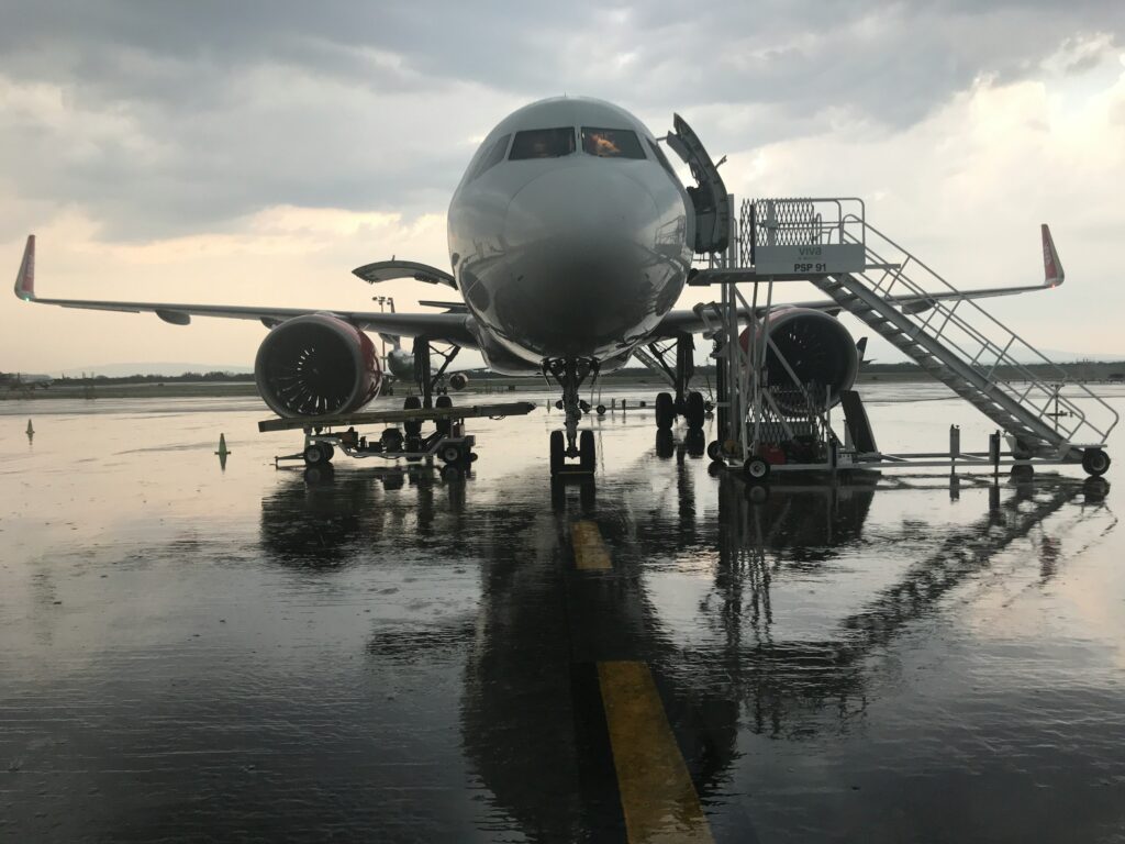 A plane standing at an airport, wet ground, grey skies