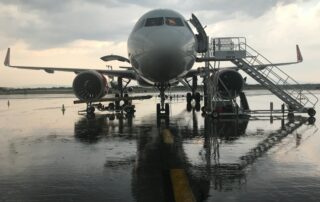 A plane standing at an airport, wet ground, grey skies